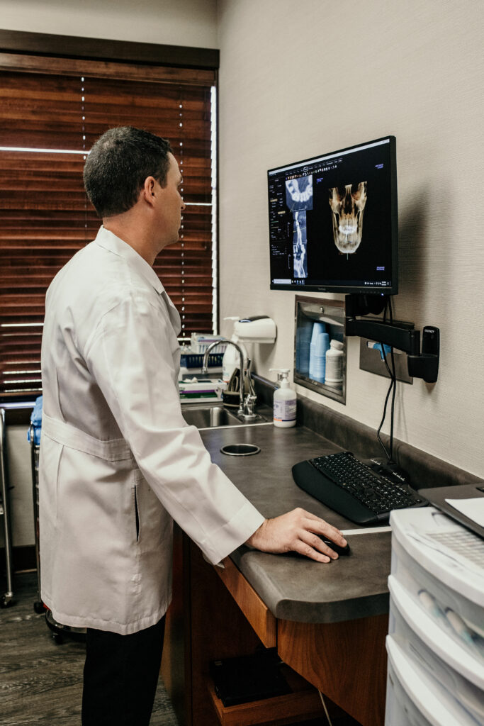 Dr. Atwood looking at oral x-rays and helping a patient